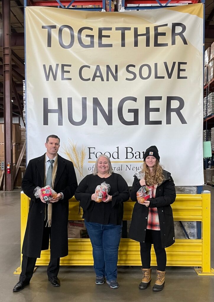 AJ and Jamie pose with the Chief Development Officer of the Food Bank of Central New York, holding items they brought in for donation from their food drive.