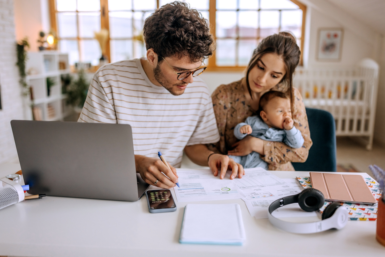 Young couple with baby, looking over finances