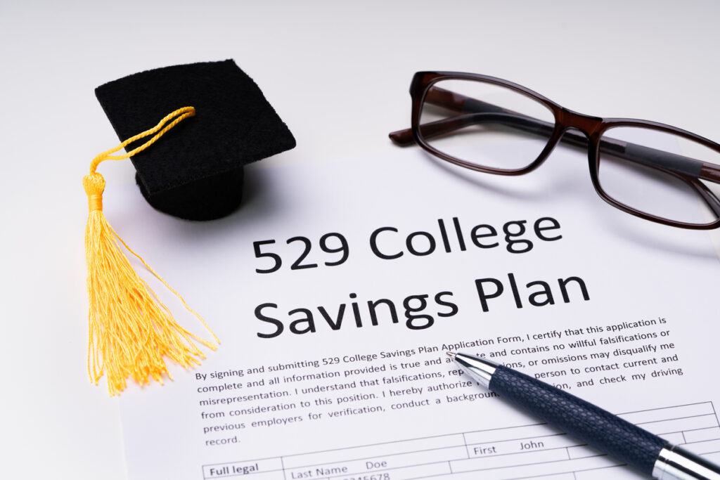 529 College Savings Plan application, with pen, eyeglasses, and small graduation cap